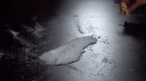 Person Spreading Sugar On Table In Dark Room GIF