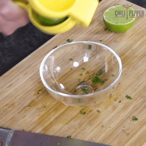 Person Squeezing Lime on Cutting Board With Chili Pepper