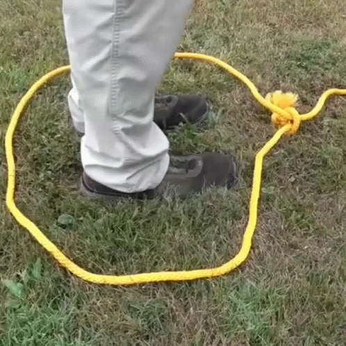 Person Standing In Grass With Yellow Rope GIF