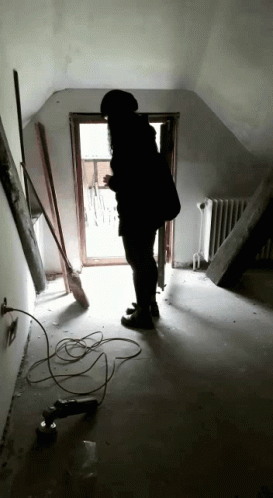 Person Standing in Hallway with Broom and Drill