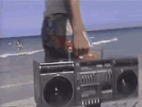 Person Standing Next to Boombox on Beach