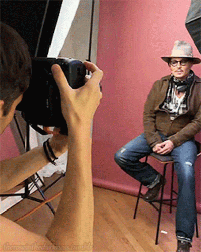 Person Taking Photo of Man in Hat and Scarf