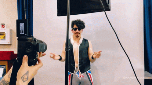 Person Taking Picture of Man in Vest and Sunglasses