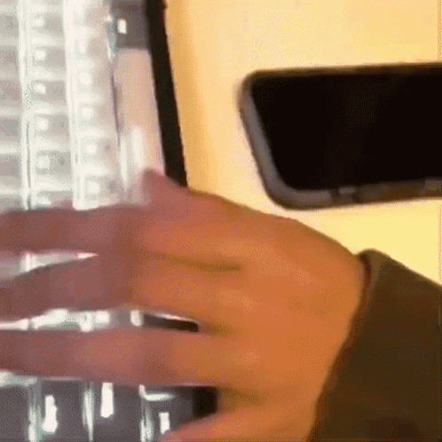 Person Typing on Keyboard Next to Phone