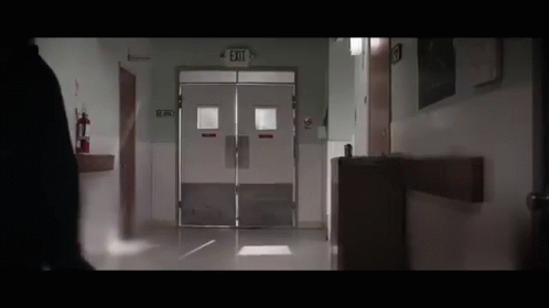 Person Walking Down Hospital Hallway With Exit Sign