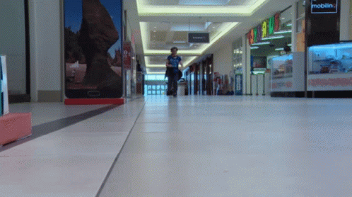 Person Walking In Mall With Mobilin Sign GIF