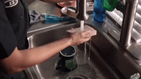 Person Washing Mug in Kitchen Sink