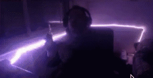 Person With Headphones in Dark Purple Room