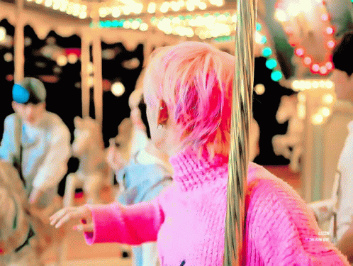 Person With Pink Hair in Front of Merry Go Round
