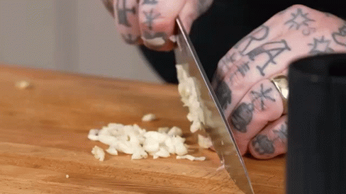 Person With Tattooed Fingers Chopping Garlic