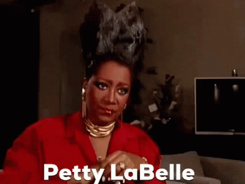 Petty La Belle in Red Jacket and Gold Necklace