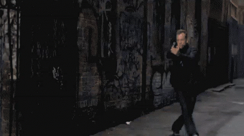 Pixelated Man Holding Gun in Front of Graffiti Wall