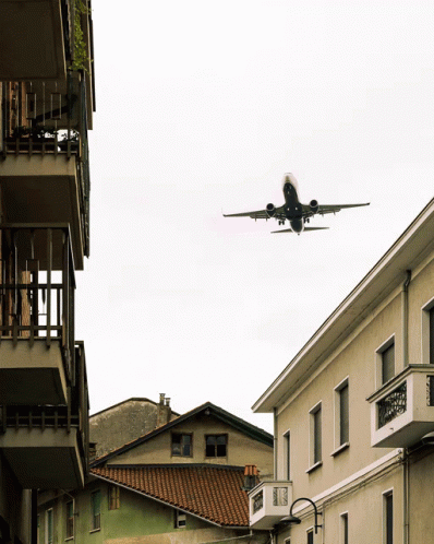 Plane Flying Over Building With Balcony