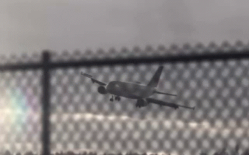 Plane Flying Over Chain Link Fence GIF
