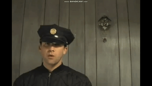 Police Officer in Black Uniform by Wooden Wall