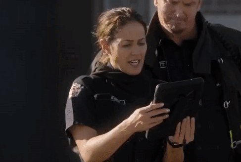 Policewoman Looking at Tablet With Man Behind