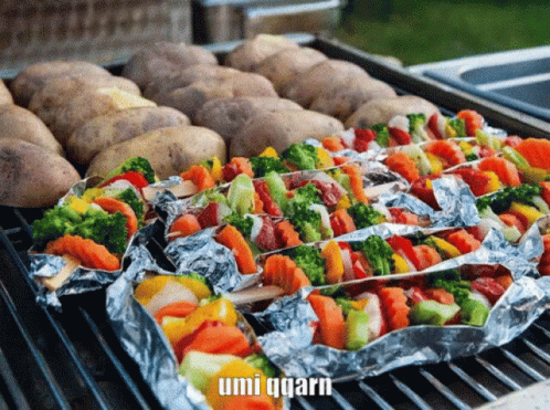 Potatoes And Vegetables Wrapped In Aluminum Foil On A Grill With Umi Qqarn In The Corner GIF