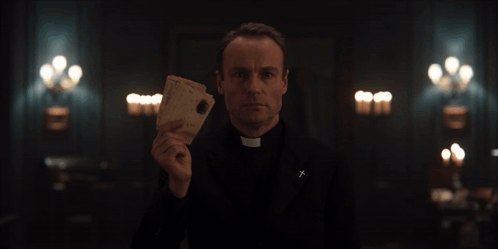 Priest Holding Paper With Cross on Jacket