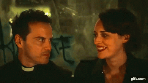 Priest Making Funny Face Talking To Woman In Dark Room GIF