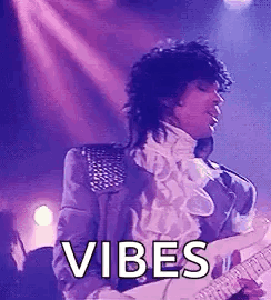 Prince Is Playing A Guitar On Stage While Wearing A Purple Jacket . GIF