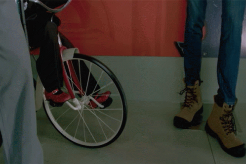 Puppet Riding Bike Next To Woman's Jeans GIF