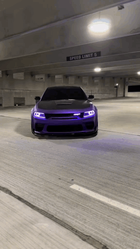 Purple Car Driving Under Speed Limit Sign in Parking Garage
