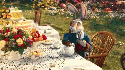 Rabbit Sitting at Table with Flowers and Cake