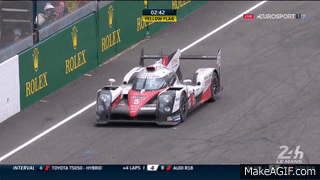 Race Car Driving Down Track with Rolex Advertisement