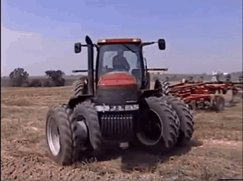 Red and Black Tractor Driving Across Field