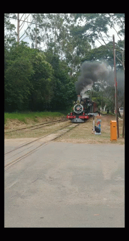 Red and Black Train Going Down Tracks With Smoke