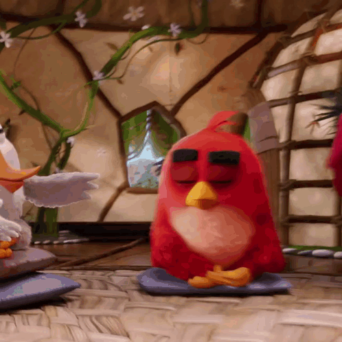 Red Angry Bird Sitting on Blue Pillow With Eyes Closed
