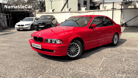 Red BMW Parked With Other Cars Saying Namaste Car