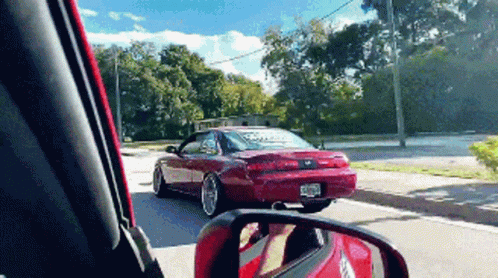 Red Car Driving Down Street With License Plate Saying Ecr