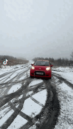 Red Car Driving on Snow Covered Road
