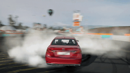 Red Car Driving With Tire Smoke