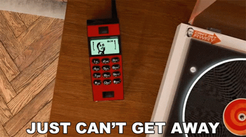 Red Cell Phone Next to Record Player Just Can't Get Away