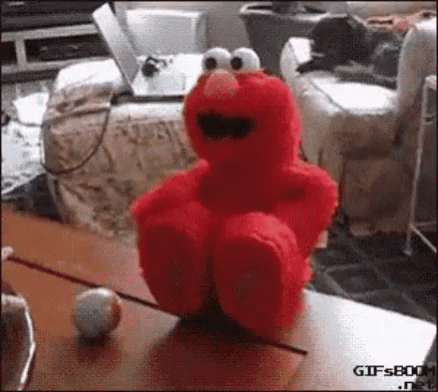 Red Elmo Stuffed Animal Sitting Next To Ball GIF