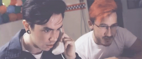 Red Hair Man Talking on Phone Next to Man With Glasses