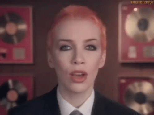 Red Hair Woman In Suit And Tie Before Plaques GIF