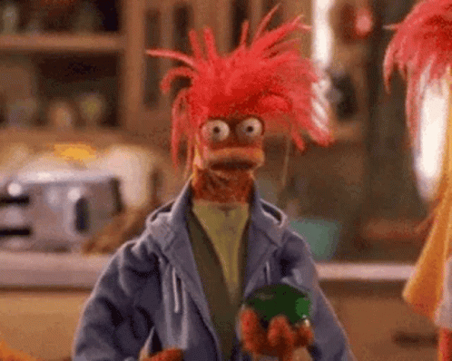 Red-Haired Muppet in Blue Jacket Holding Green Jar