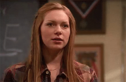 Red-Haired Woman At Chalkboard With Windblown Hair GIF