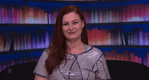 Red-Haired Woman Laughing in Front of Bookshelf