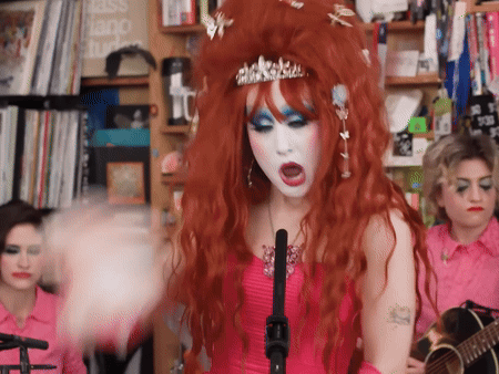 Red-Haired Woman Singing into Microphone with Crown