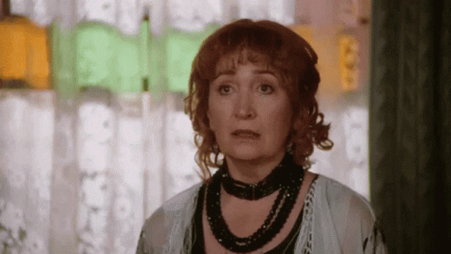 Red-Haired Woman With Black Necklace Looking At Camera GIF