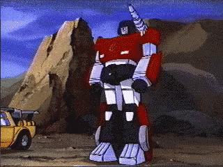 Red Robot With Horn Standing in Front of Yellow Truck
