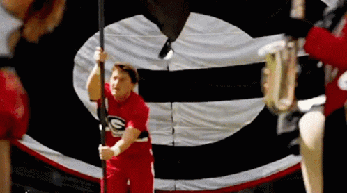 Red Shirt Man Holding Flag With Letter G GIF
