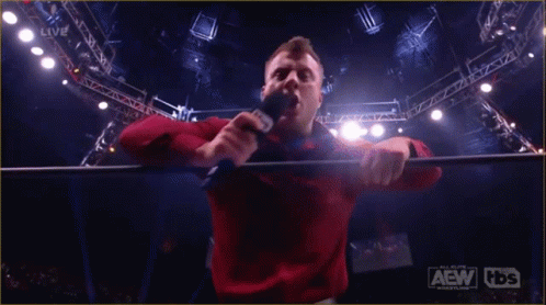 Red Shirt Man Holding Microphone AEW HDS Sign