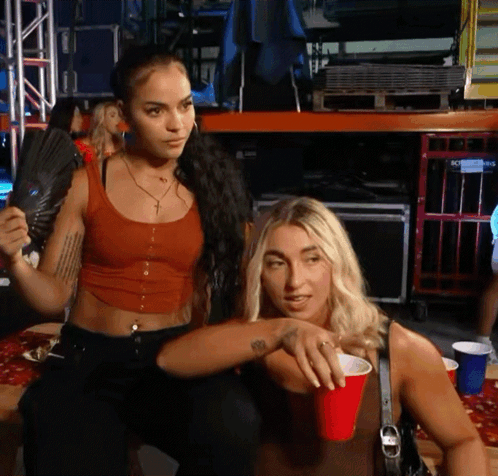 Red Tank Top Woman Holds Fan Near Blonde With Red Cup