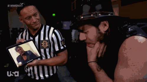 Referee Shows Wrestler Picture, Other Wrestler Looks Down GIF
