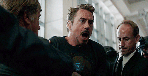 Robert Downey Jr. Is Being Held By A Group Of Men While Wearing A Black T-Shirt . GIF